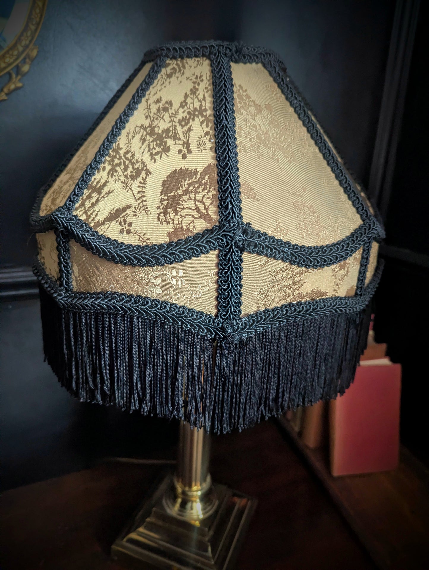 Decorative lamp with a patterned shade and fringes on a dark background