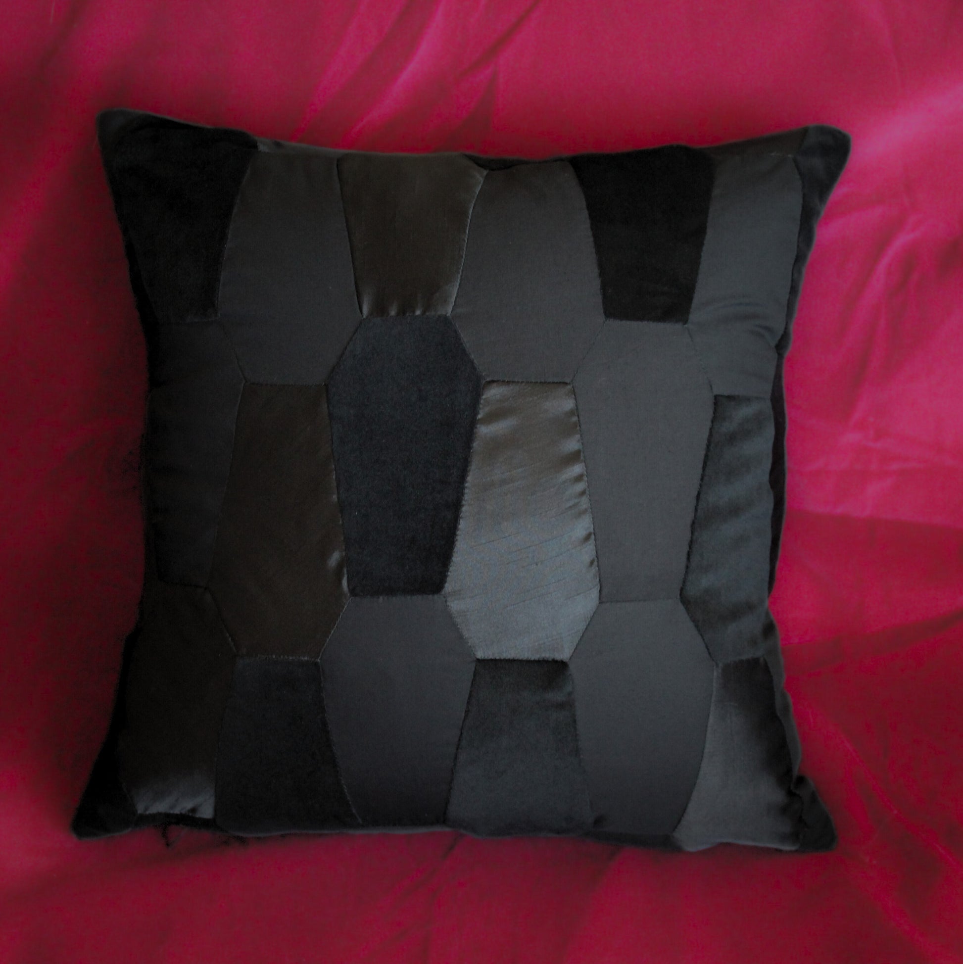 Black coffin patchwork cushion from Joely Ball Home on a red velvet background.
