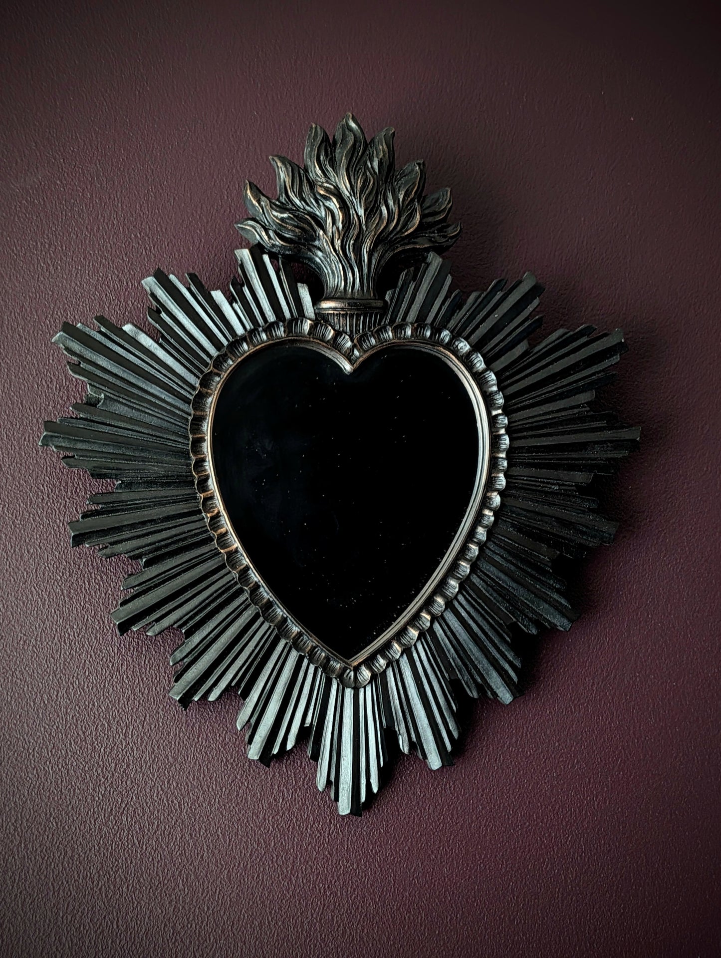 A black sacred heart mirror on a deep purple wall