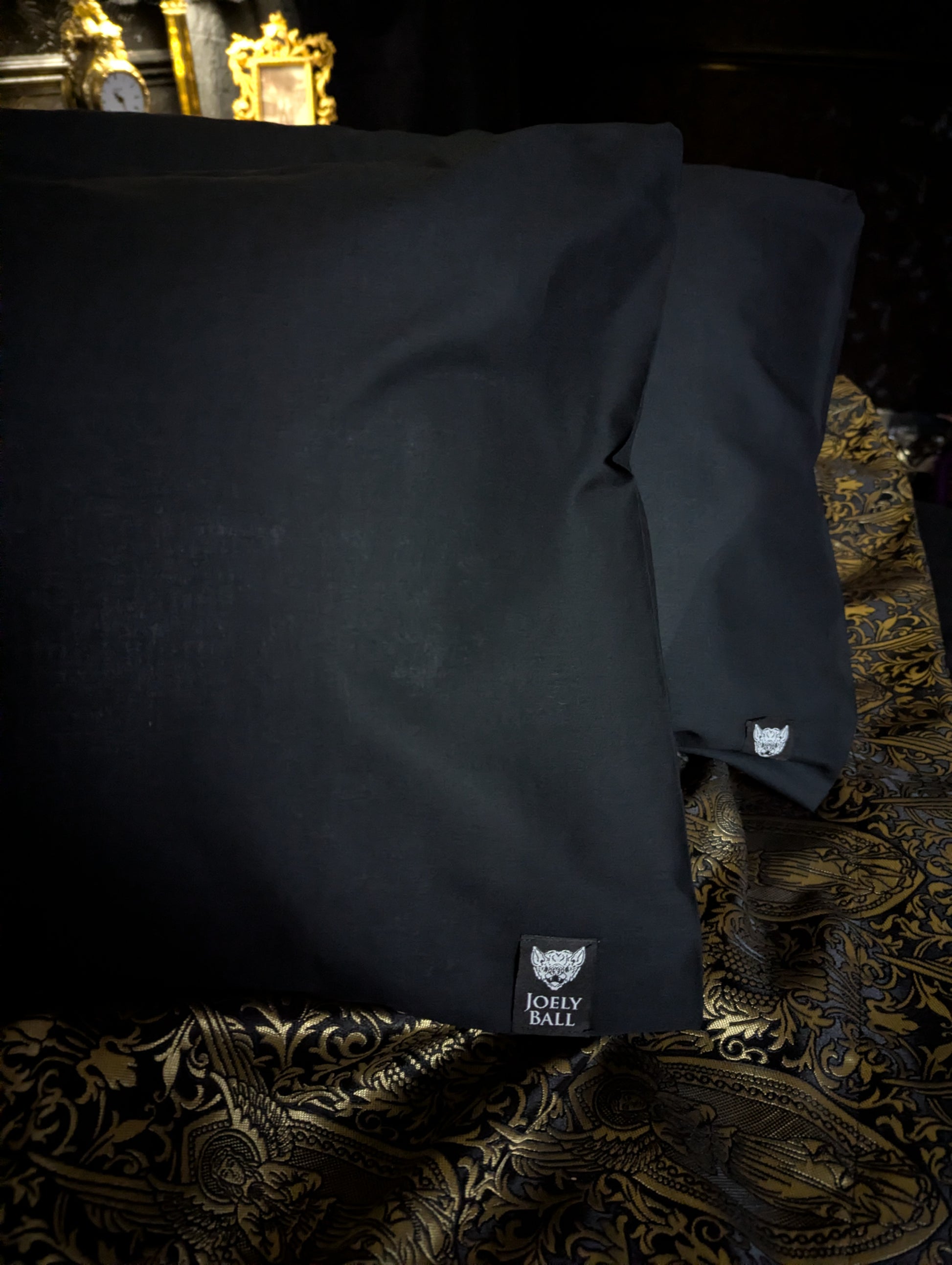 Black pillowcases with a brand logo in a Victorian Gothic bedroom.