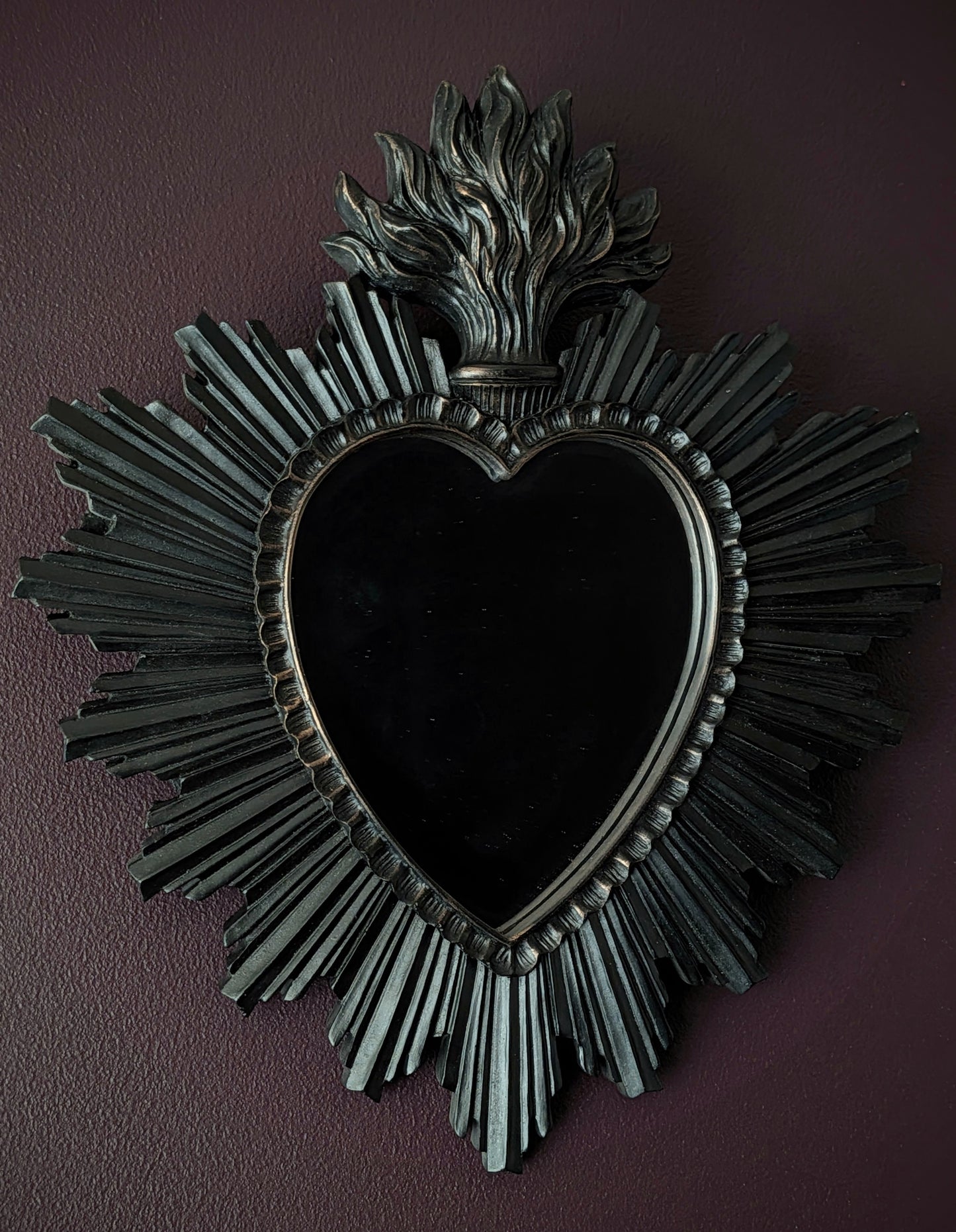 A Gothic black sacred heart style mirror on a purple wall