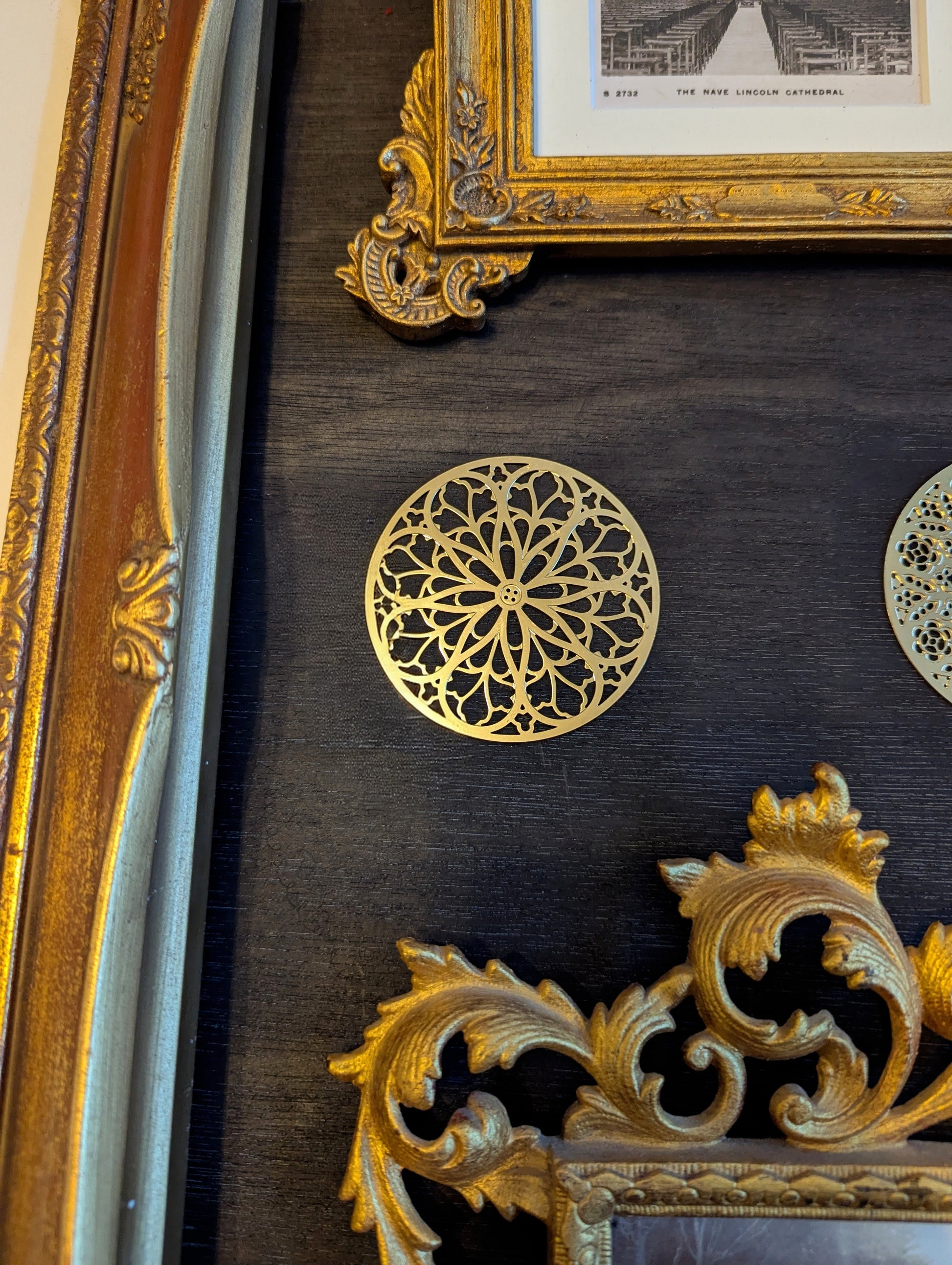 Decorative gold circular rose window ornament on a dark surface with ornate gold frames.