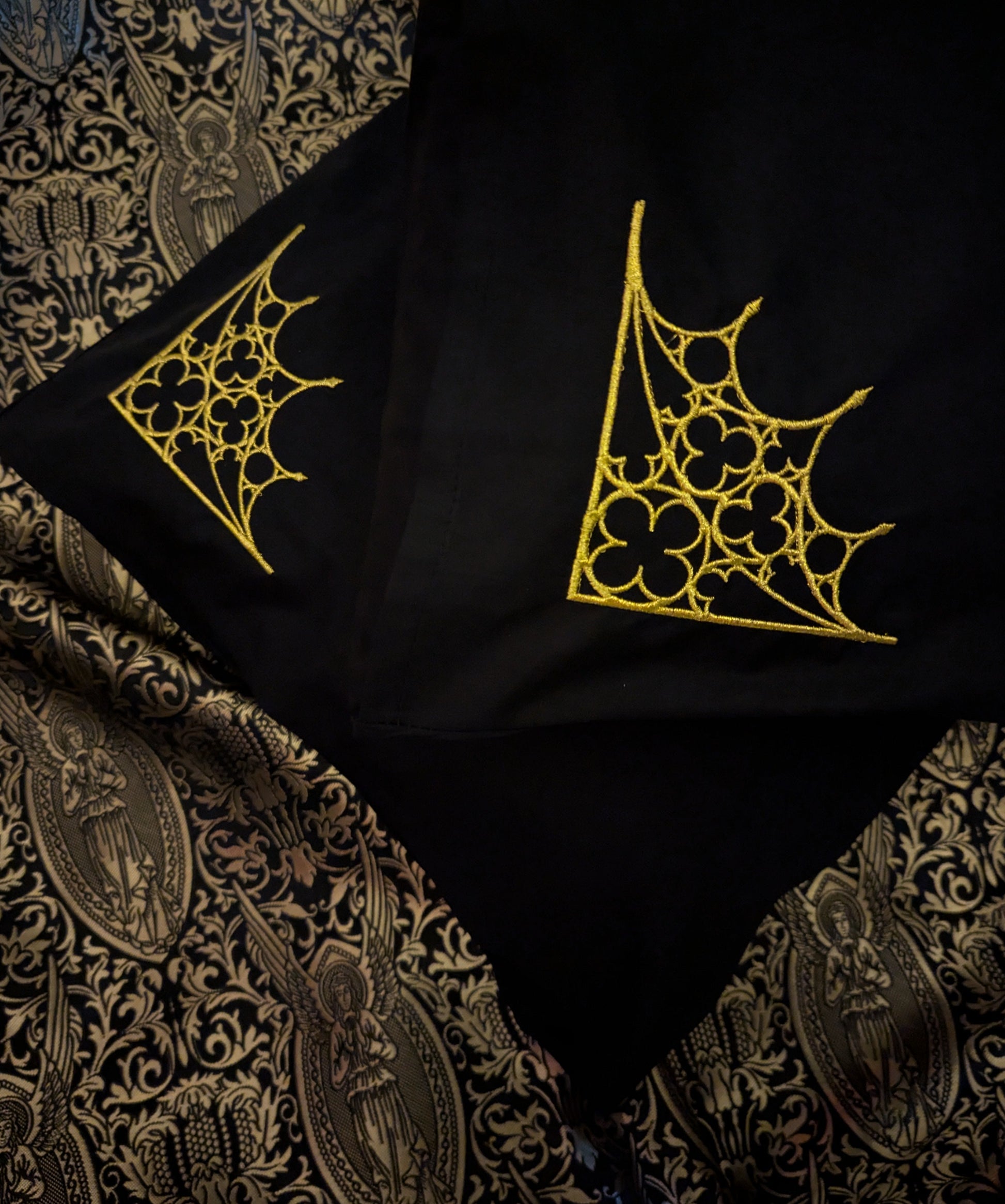 Black pillowcases embroidered with a tracery design in gold on a gold angel fabric background 