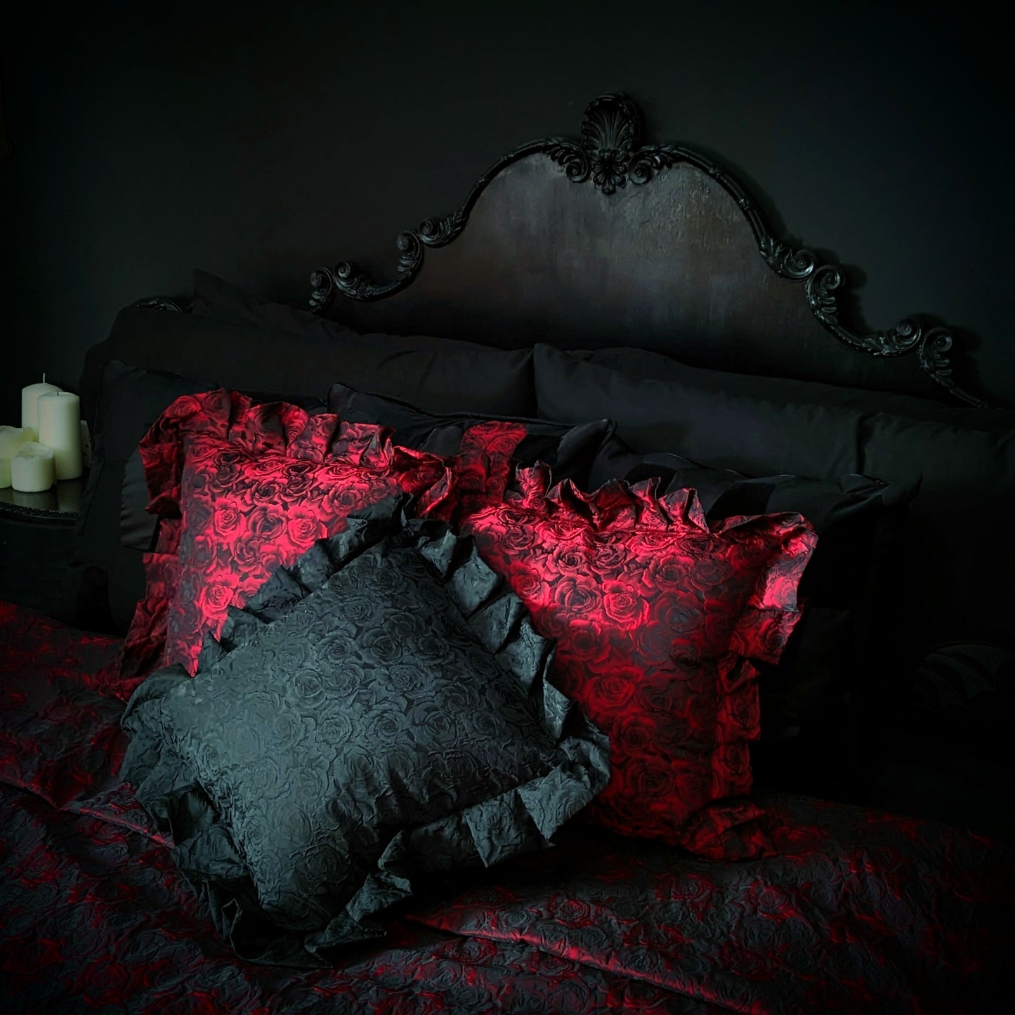 Luxurious gothic ruffled cushions in red and black with a rose pattern, displayed on a bed with dark bedding.