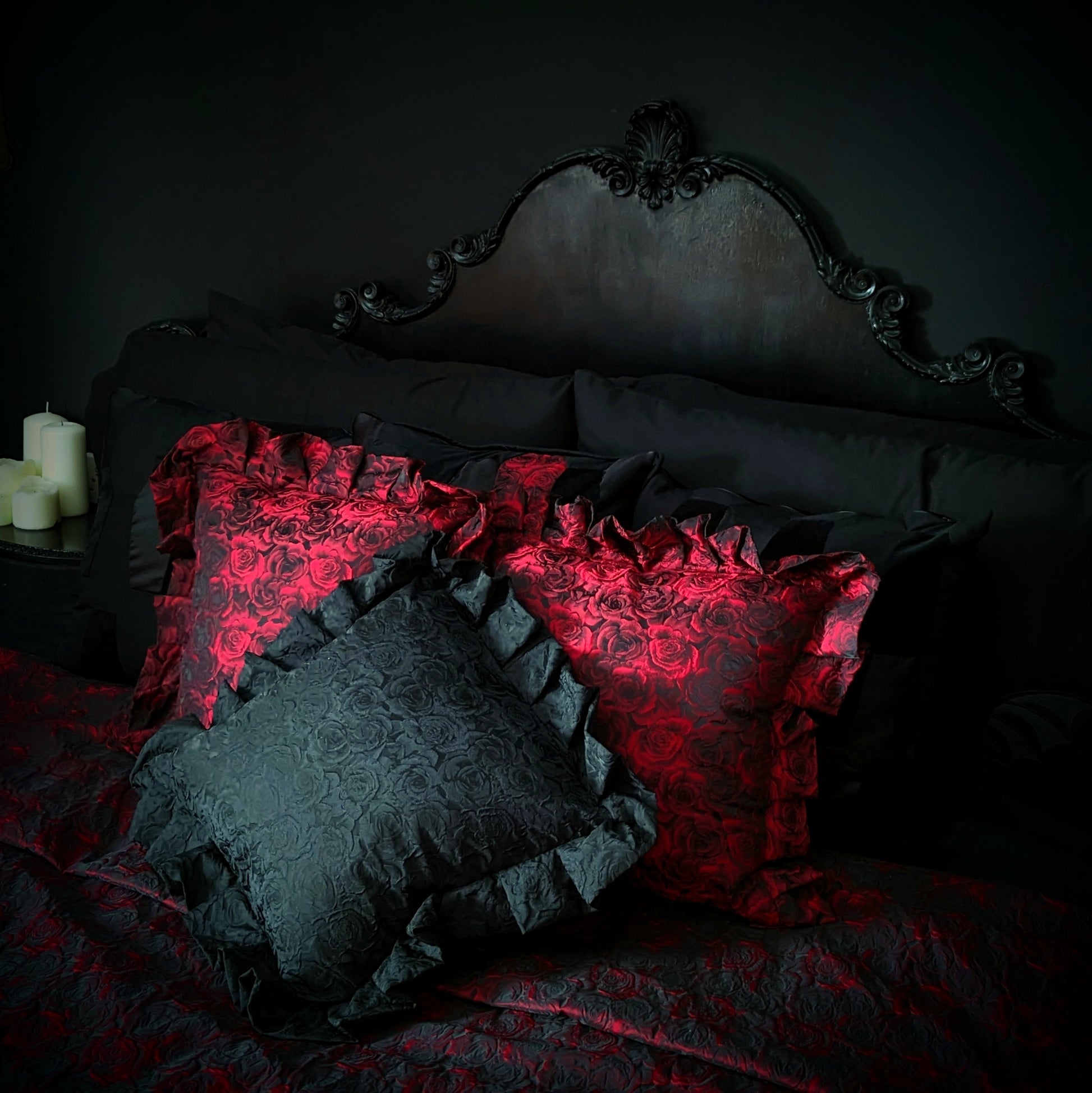 Luxurious gothic ruffled cushions in red and black with a rose pattern, displayed on a bed with dark bedding.