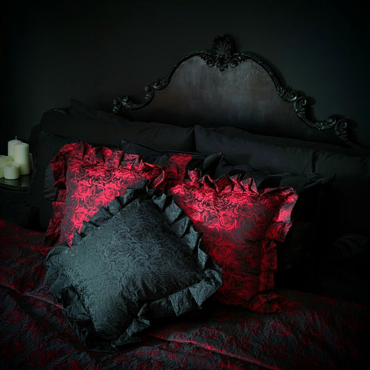 Luxurious gothic ruffled cushions in red and black with a rose pattern, displayed on a bed with dark bedding.