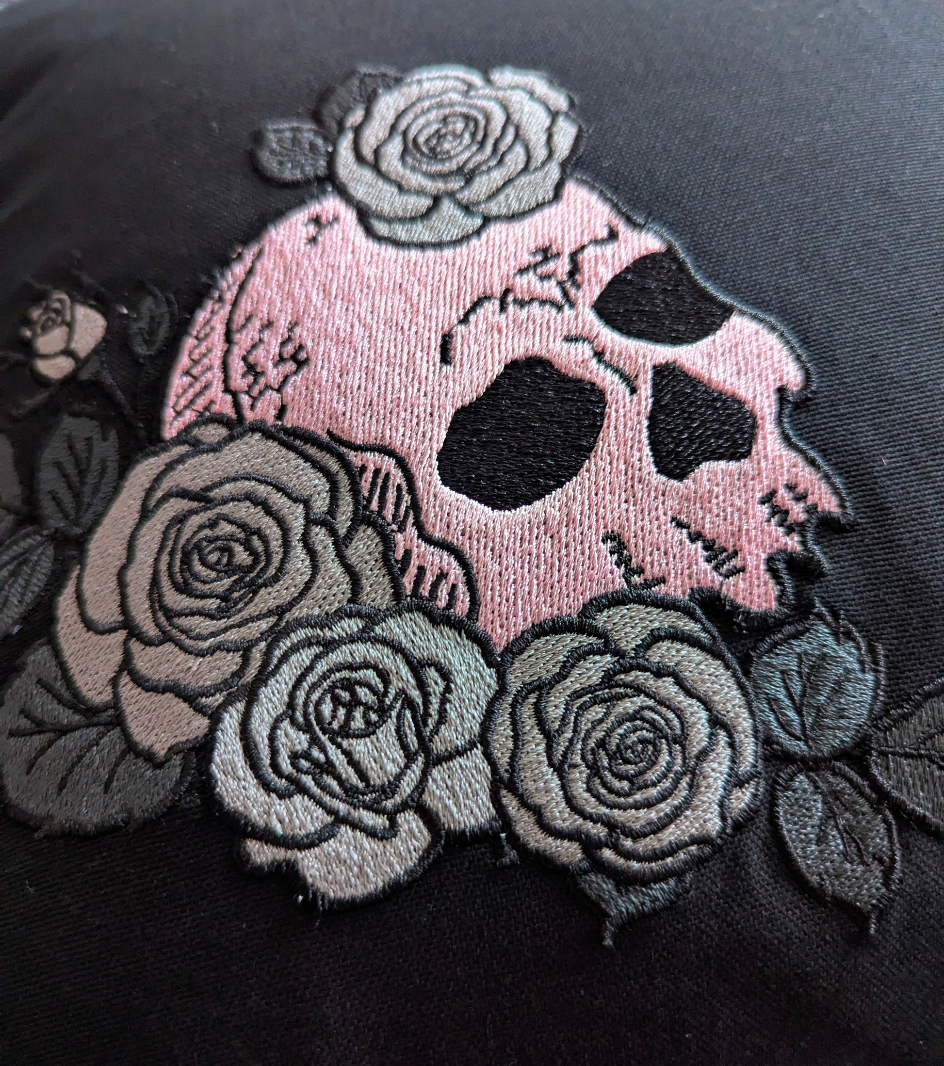 Embroidered skull design with roses on a black fabric background