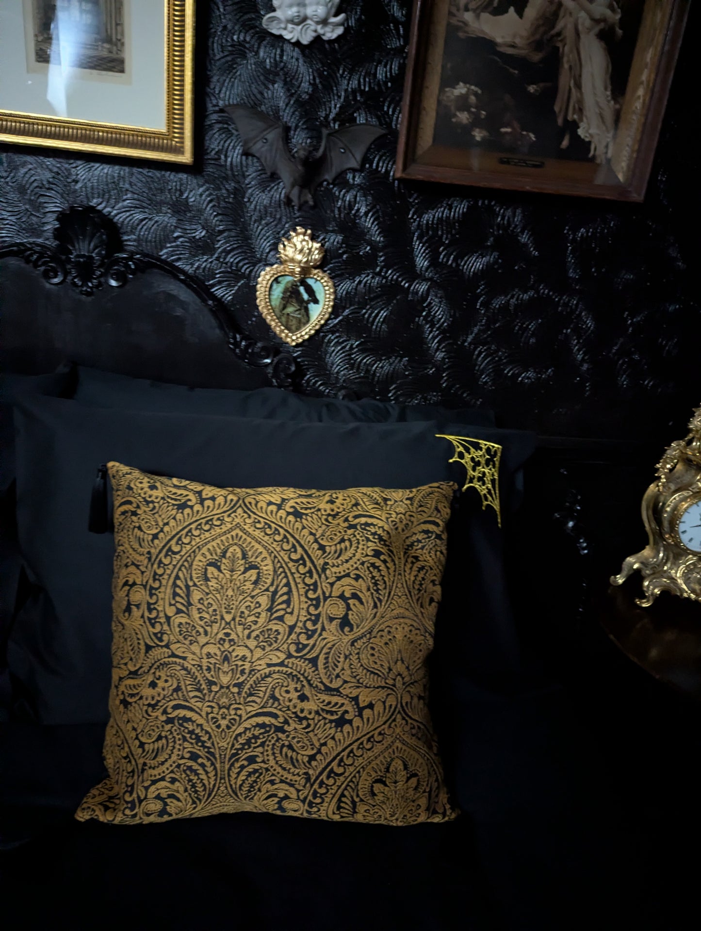 Decorative gold pillow on a dark surface with ornate wall art in the background
