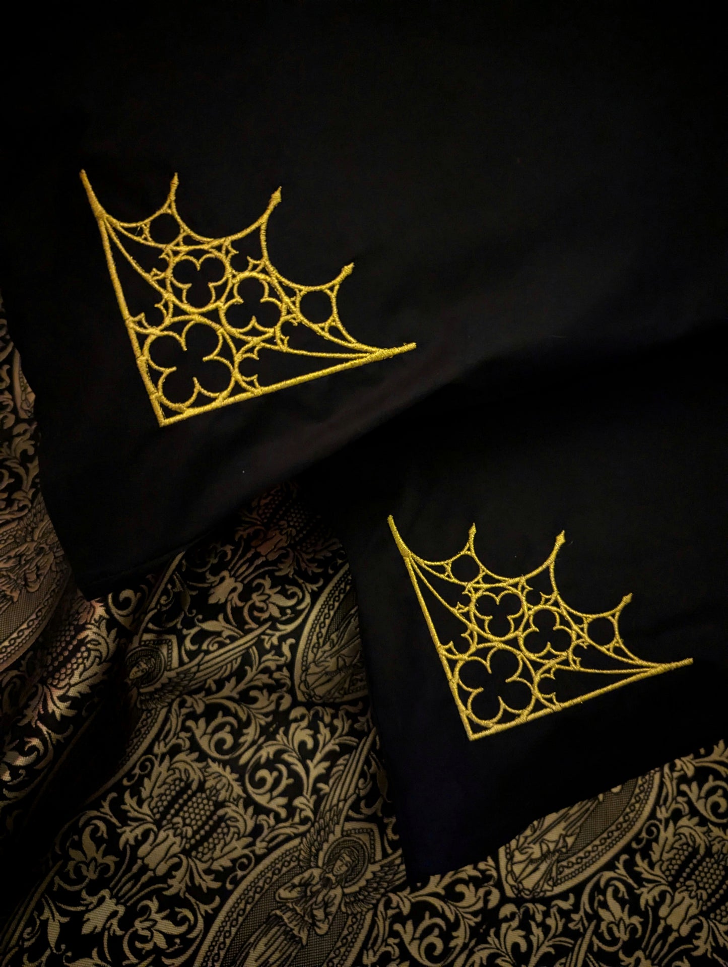 Black pillowcases embroidered in gold with a Gothic tracery design on golden angel fabric 
