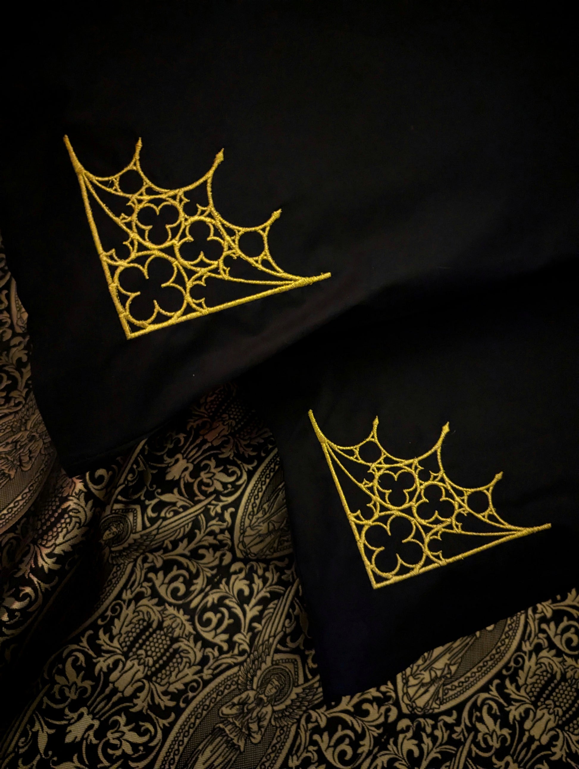 Black pillowcases embroidered in gold with a Gothic tracery design on golden angel fabric 
