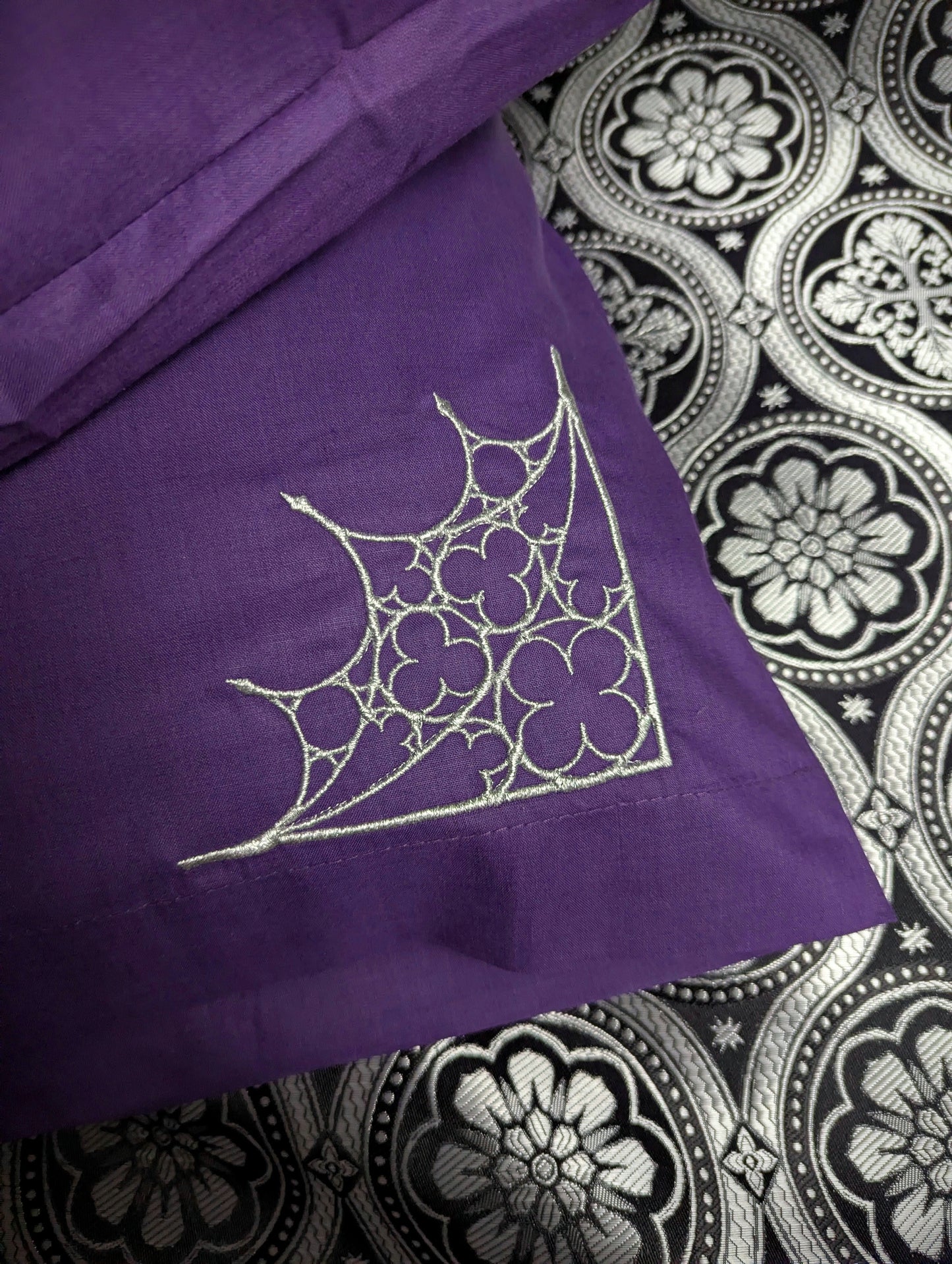 Purple pillow with silver embroidered Gothic design on a black and silver patterned background