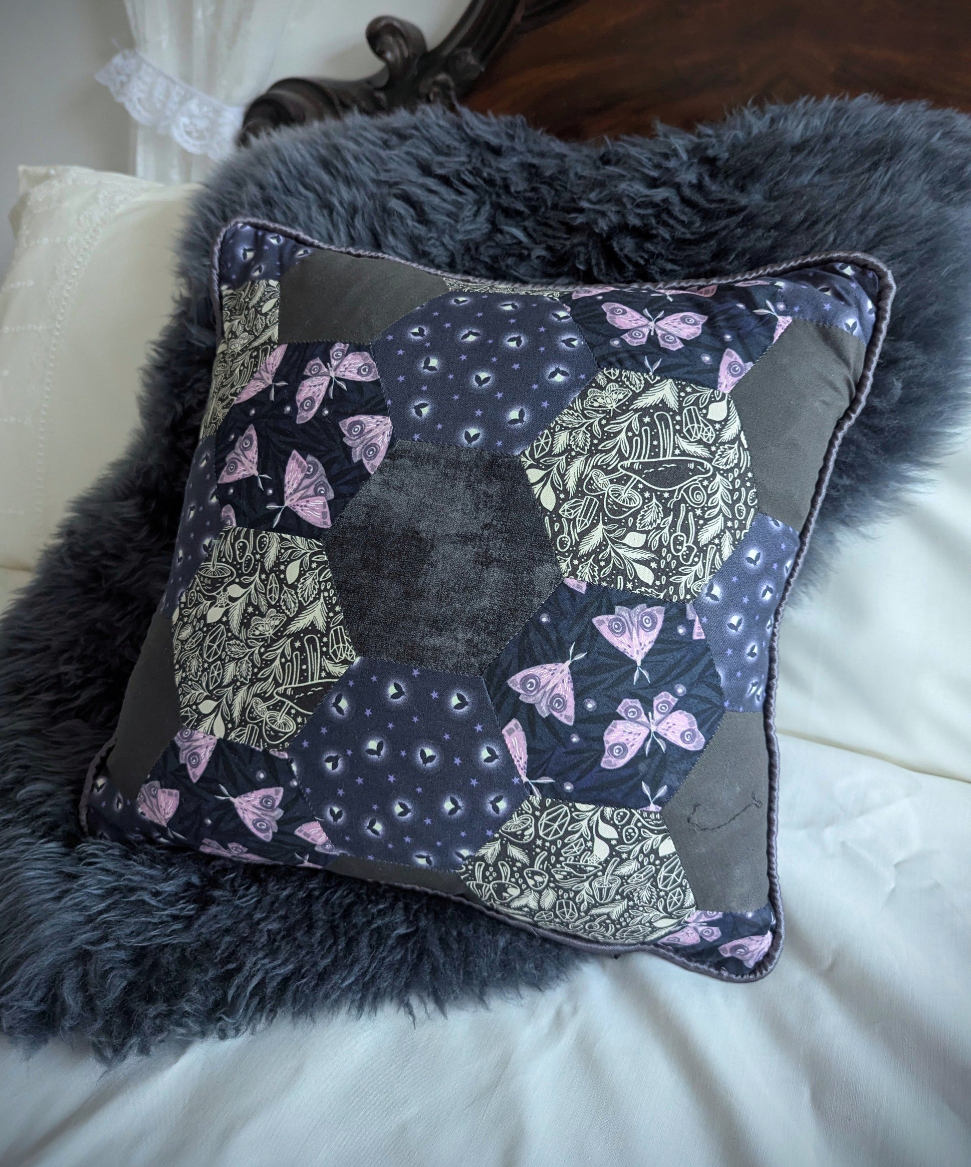 Patchwork cushion featuring moths and fireflies on a bed