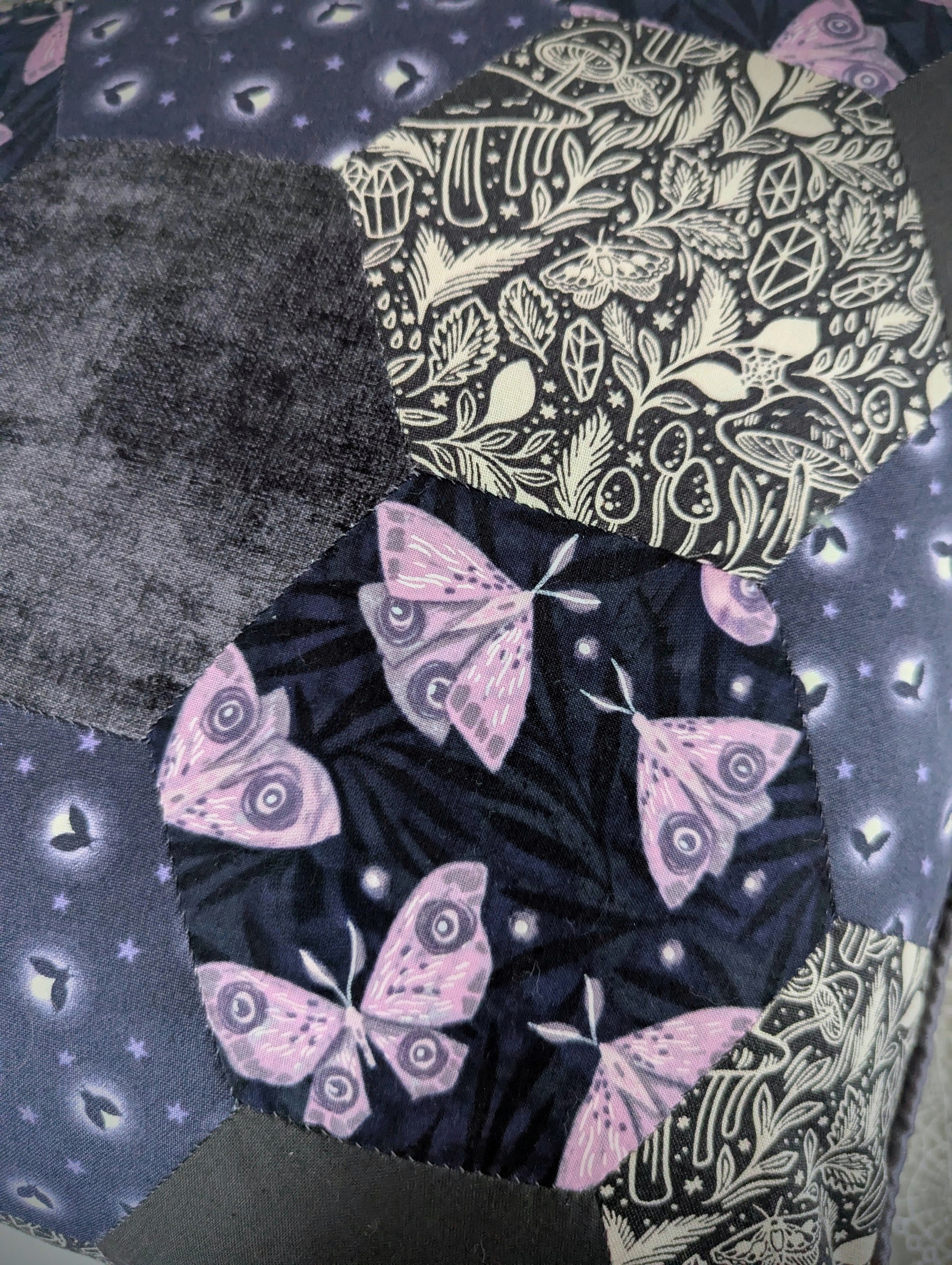 Close up of a patchwork cushion showing moth and woodland prints made of hexagons