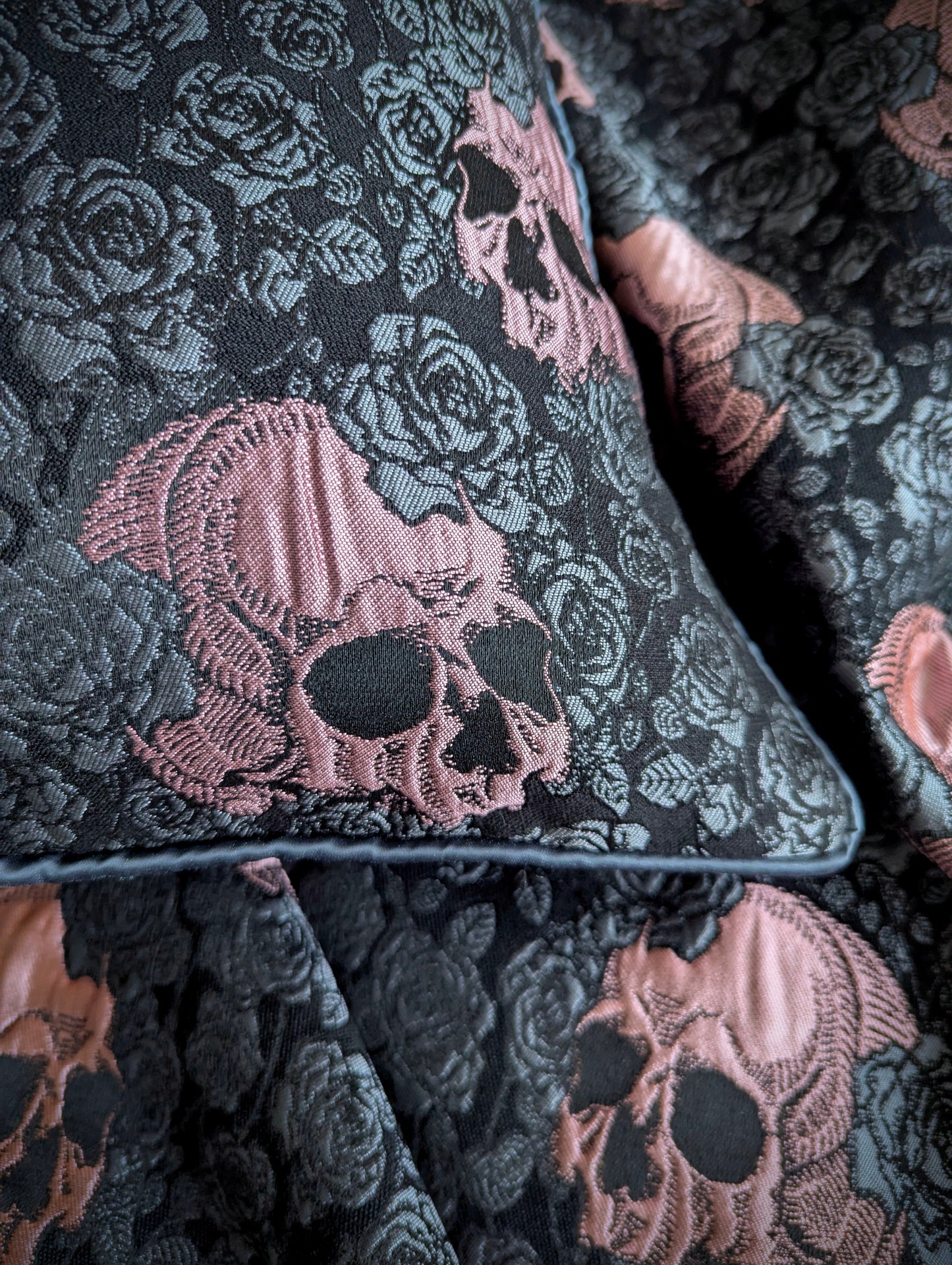 Close-up of a cushion with pink skulls and grey roses with grey piping