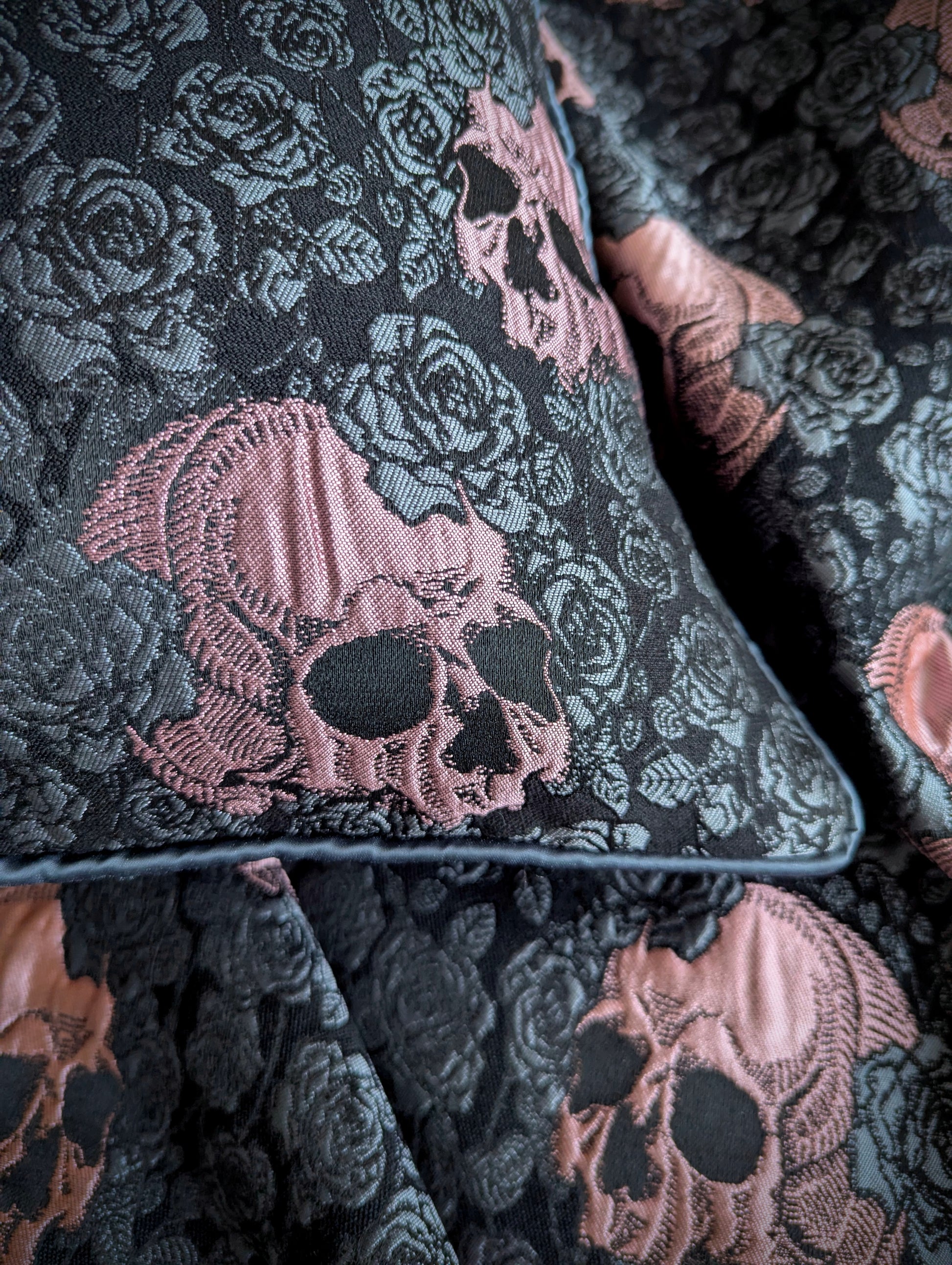 Close-up of a cushion with pink skulls and grey roses with grey piping