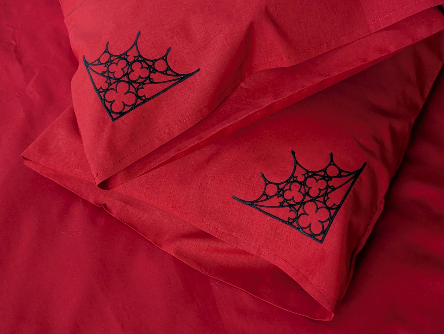 Red pillows with black Gothic tracery design on a matching red bedding background.