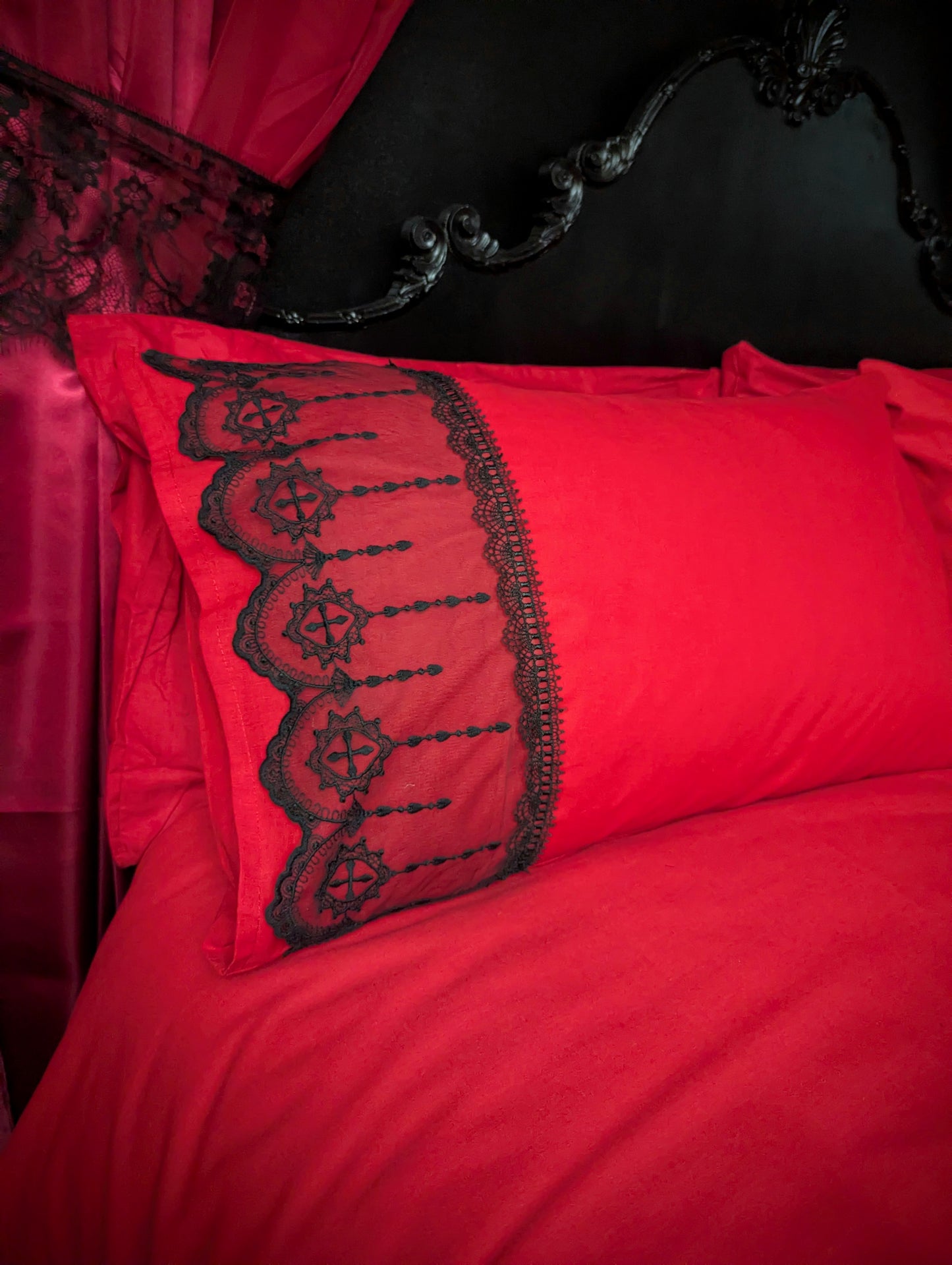 Red pillow with black lace detailing on a dark background