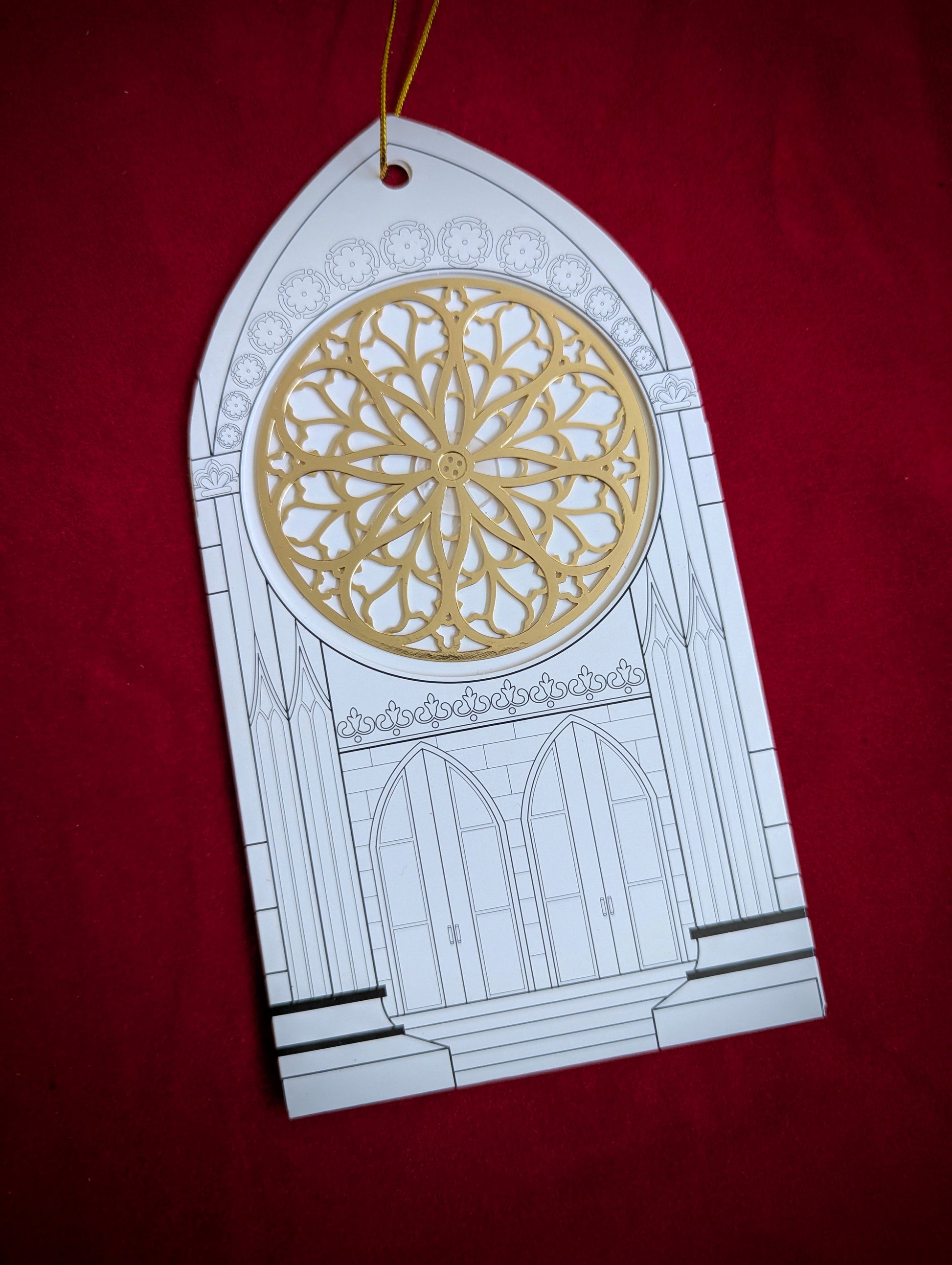 Decorative card with gothic arch and rose window design on a red background