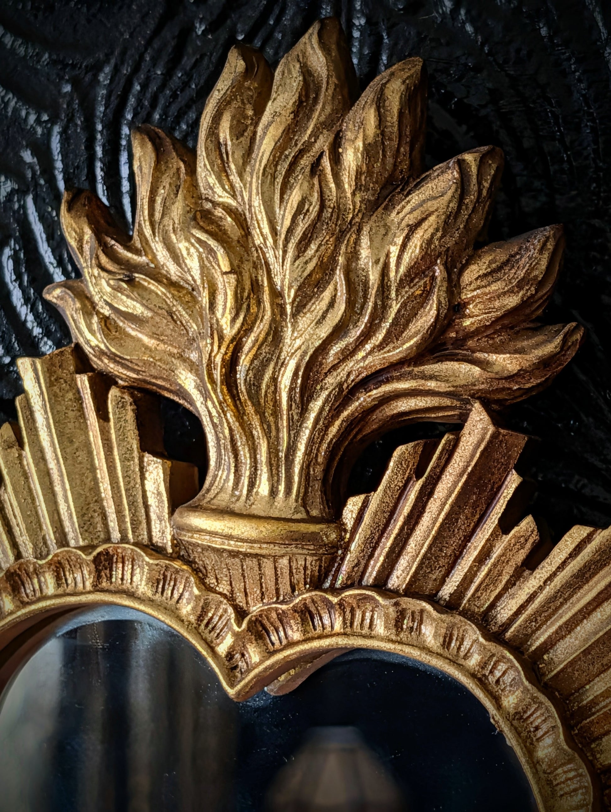 A close up of the details of a gold sacred heart style mirror 