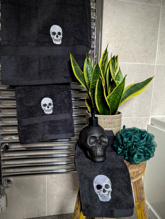 Black towels with skull designs on a towel rack in a bathroom setting.