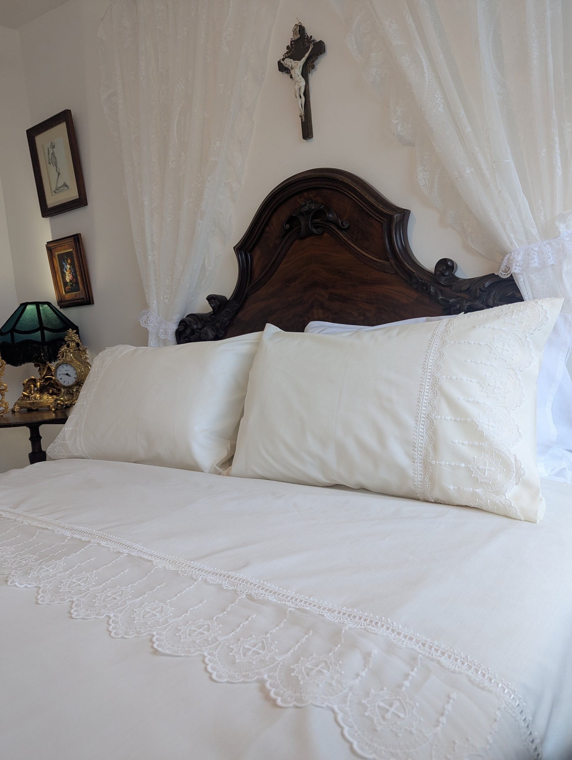 Bedroom with white bedding, wooden headboard, and decorative items on a nightstand.