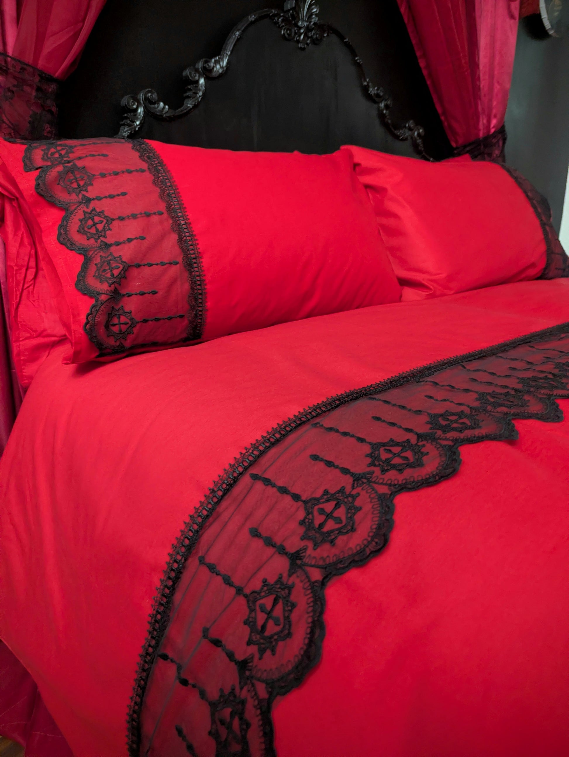 Red bedding set with black lace trim on a bed.