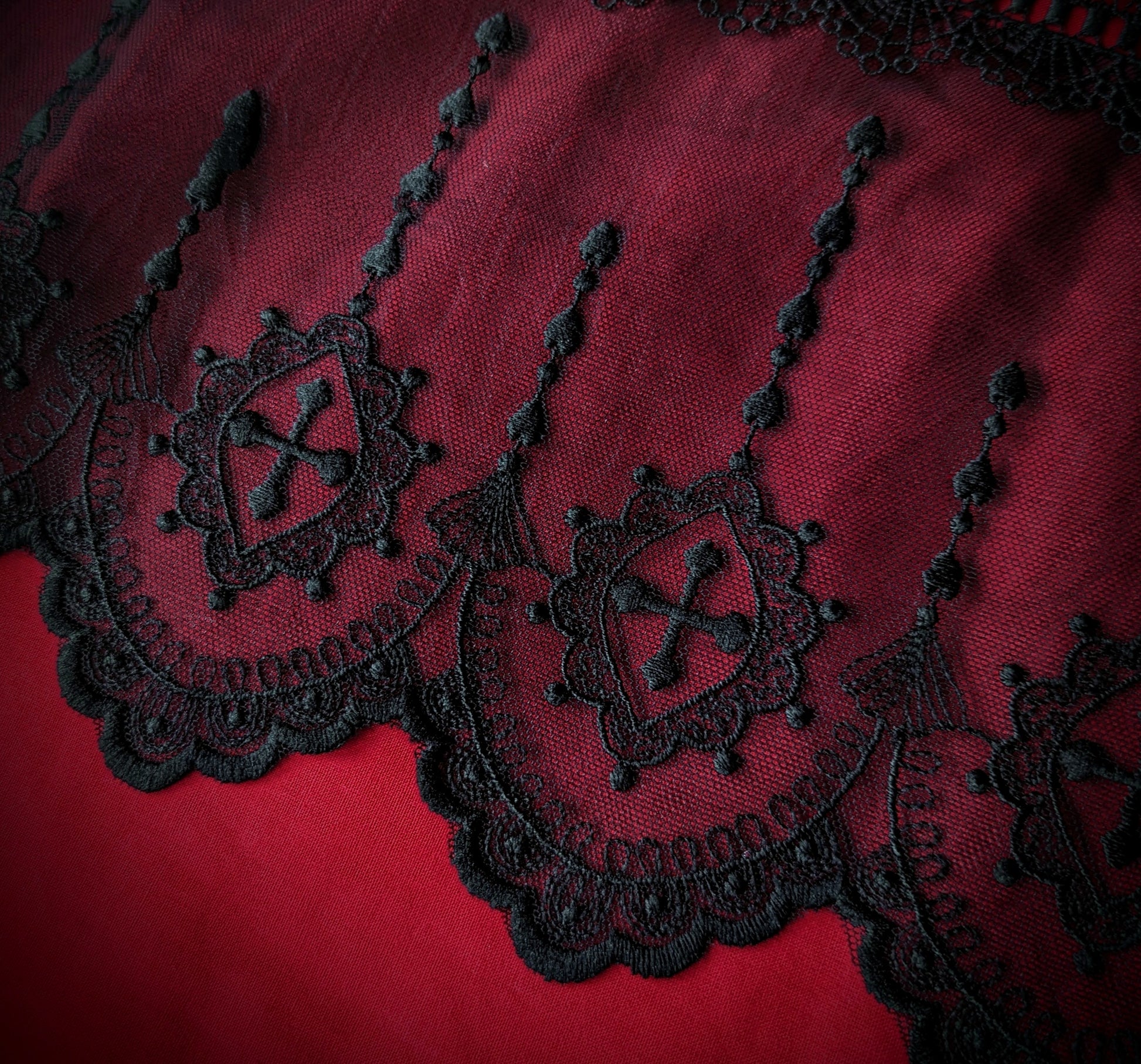 Close-up of black lace bedding on a red background, showcasing intricate patterns and design.