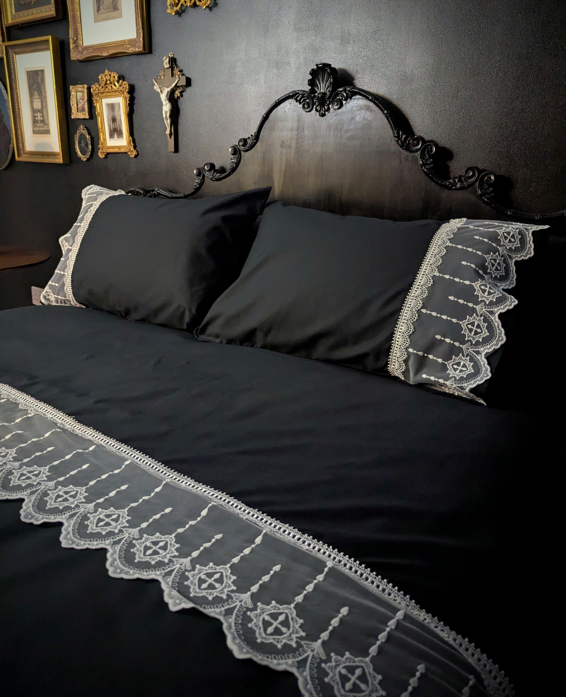 Black bedspread with white lace trim on a dark wall background