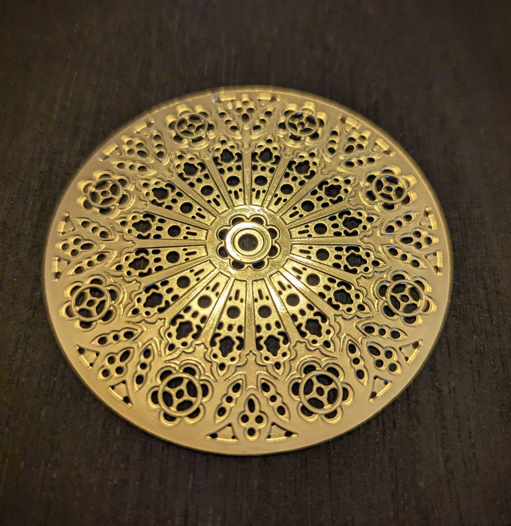 Decorative gold metal plate with intricate patterns on a dark wooden surface