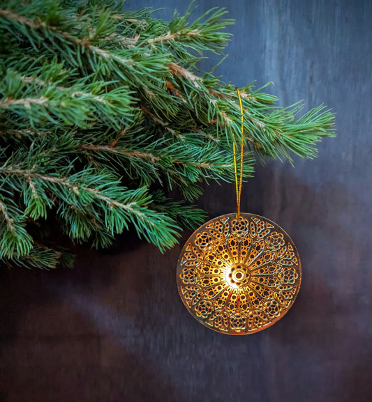 Decorative gold ornament hanging on a Christmas tree branch against a dark background