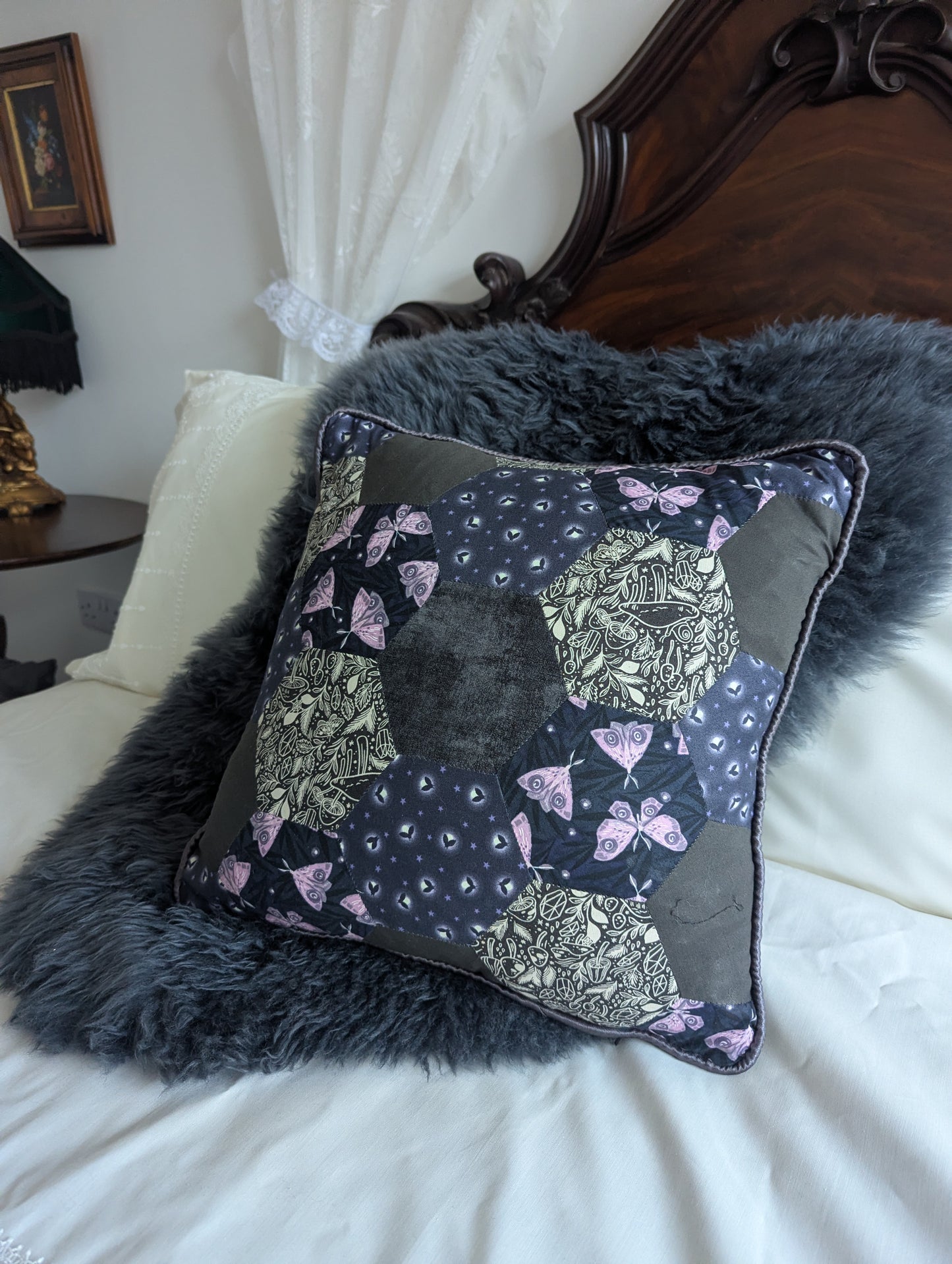 Decorative pillow with moths and fireflies on a bed with a fur throw